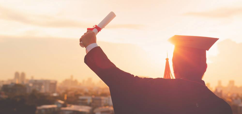 Graduate holding a degree up to the sky