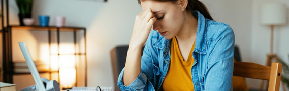 student at their desk holding the bridge of their nose