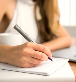 A person holding a pen writing a notebook