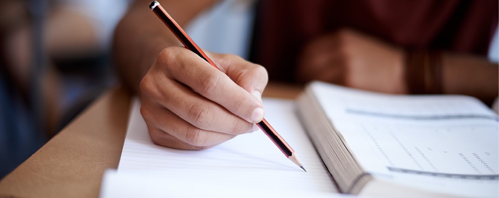 Person holding a pencil and textbook