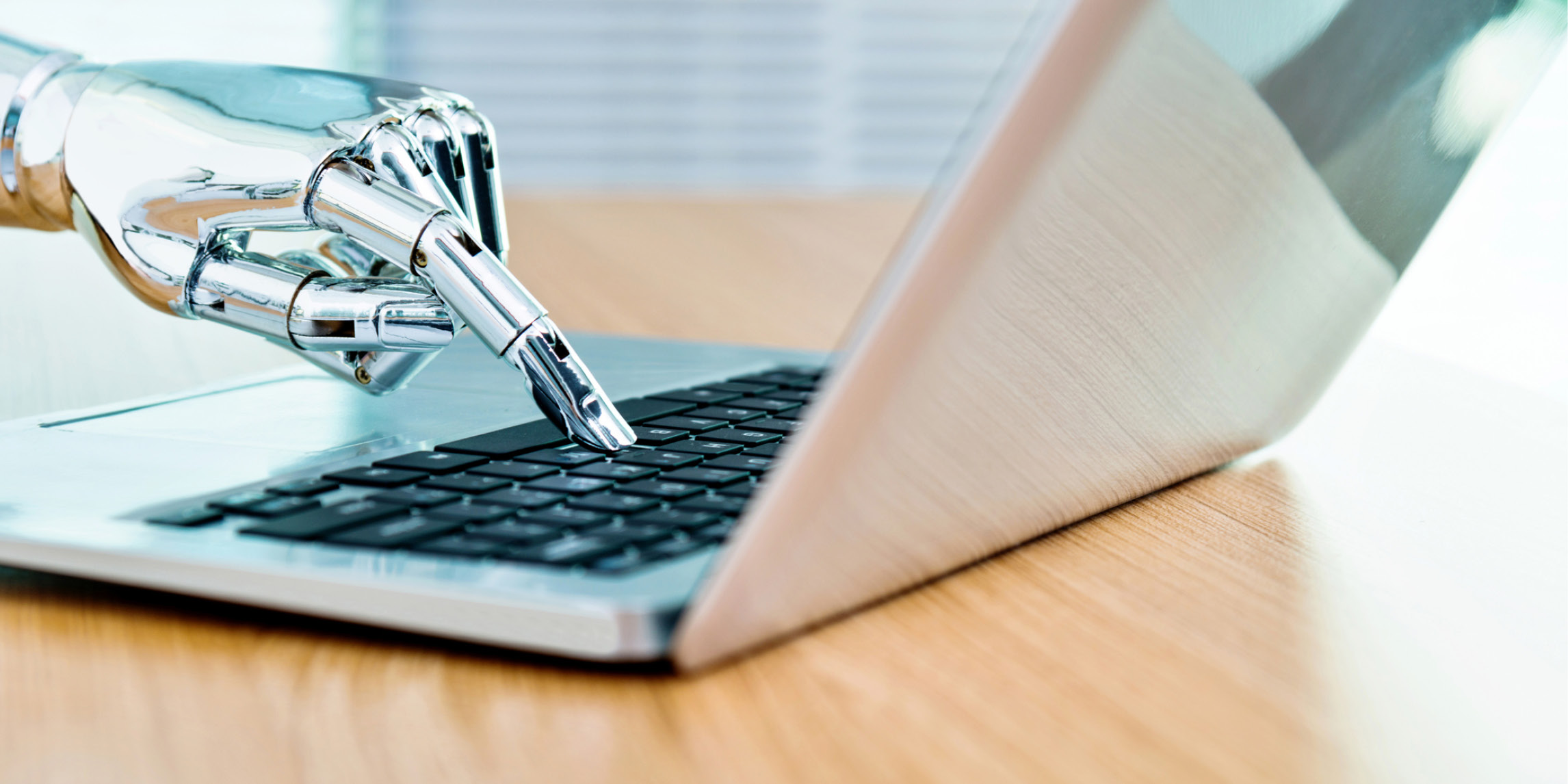 A robot hand typing on a laptop