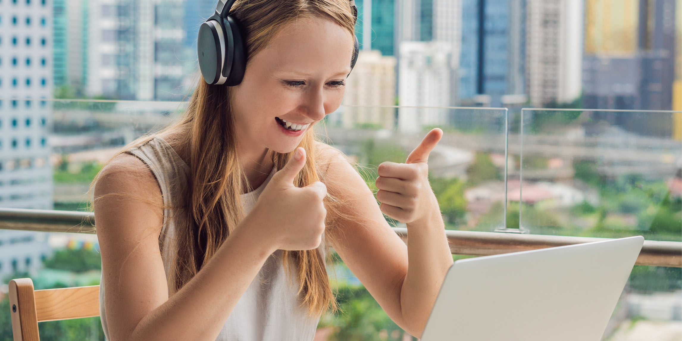 A women giving a thumb's up in front of a laptop