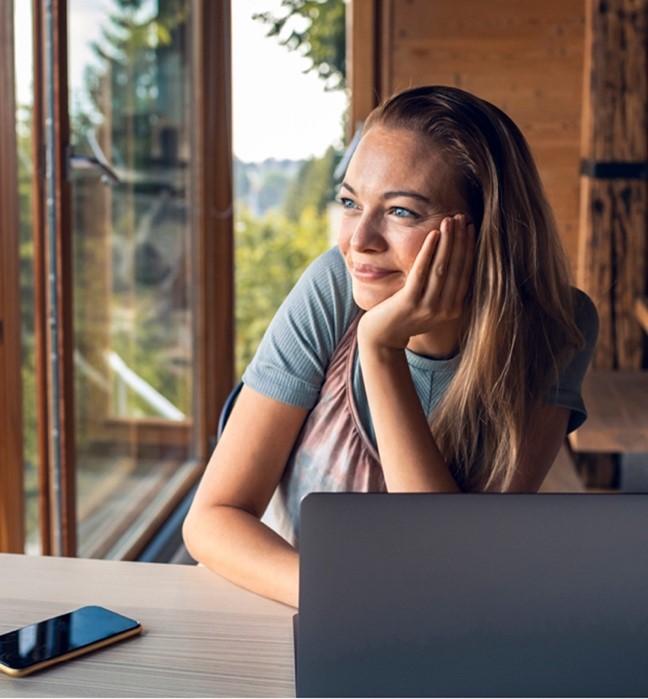 a woman with a laptop looking out the window a woman with a laptop looking out the window