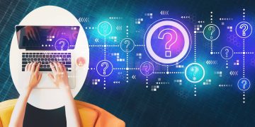 Hands typing on a laptop with digital question marks